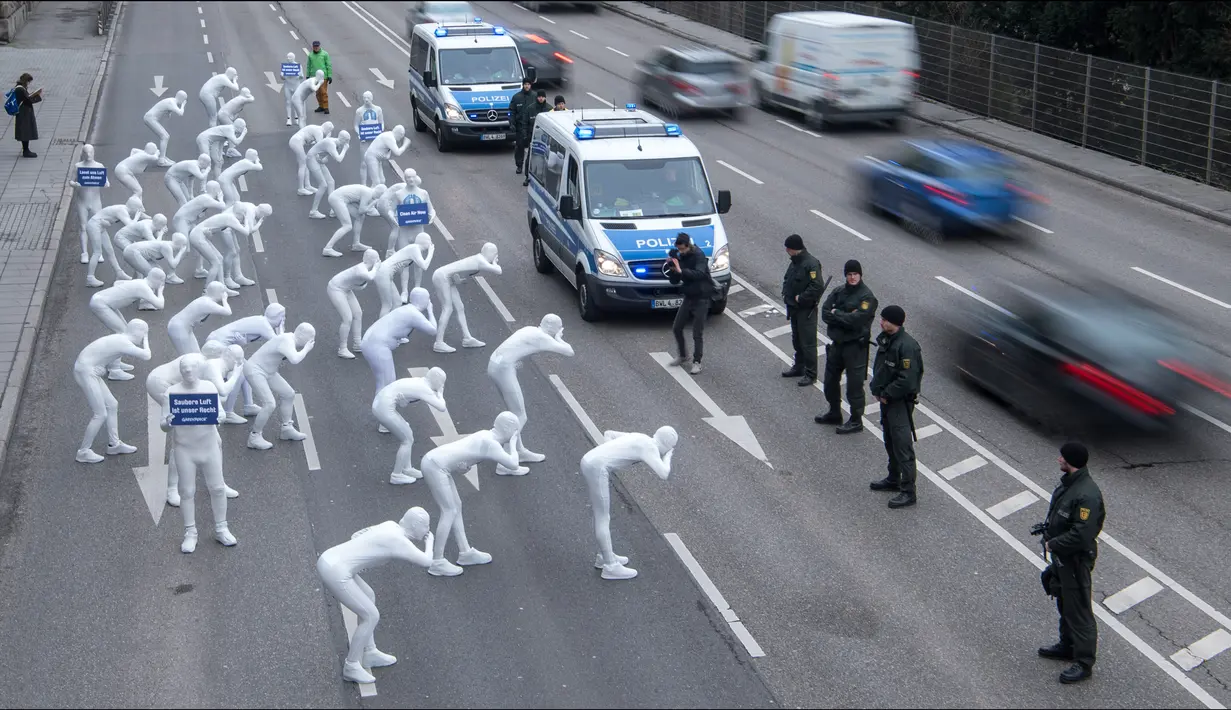 Aktivis dari Greenpeace mengenakan pakaian serba putih turun ke jalan melakukan aksi di Stuttgart, Jerman (19/2). Mereka melakukan aksi memprotes polusi yang diakibatkan oleh knalpot mobil diesel. (Sebastian Gollnow/dpa/AFP)