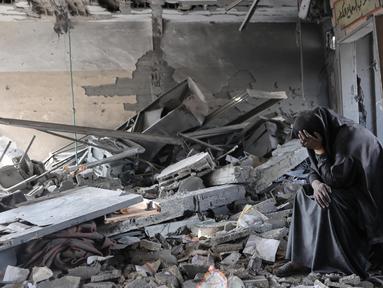 Ekspresi seorang wanita Palestina ketika duduk di tengah puing-puing Sekolah Yaffa di lingkungan Tuffah, Kota Gaza, setelah serangan Israel semalaman, pada Senin 30 Juni 2025. (Omar AL-QATTAA/AFP)
