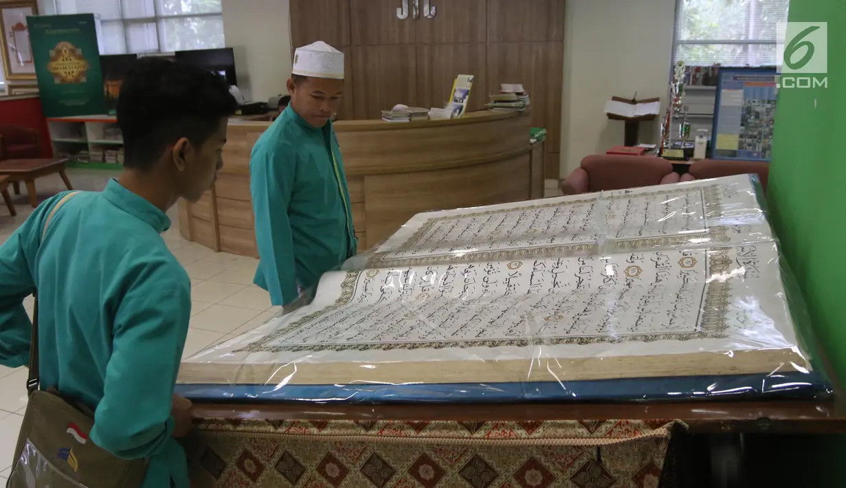 Pengunjung mengamati Alquran raksasa yang dipajang di perpustakaan Jakarta Islamic Centre, Jakarta Utara, Jumat (18/5). Alquran yang ditulis tangan tersebut sudah berusia 16 tahun. (Liputan6.com/Arya Manggala)