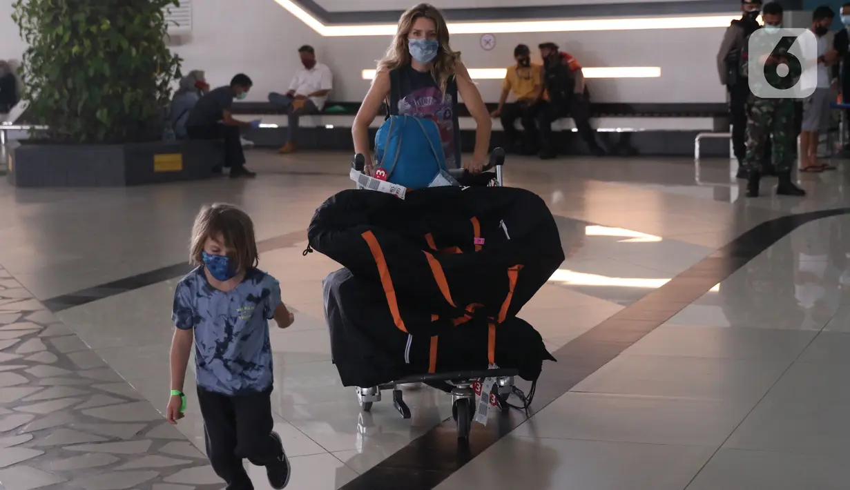 Seorang Warga Negara Asing (WNA) bersama anaknya saat tiba di Bandara Soekarno Hatta, Tangerang, Selasa (29/12/2020). Pemerintah Indonesia melarang masuk WNA dari semua negara mulai 1 hingga 14 Januari 2021 menyusul adanya varian baru COVID-19 yang ditemukan di Inggris. (Liputan6.com/Angga Yuniar)