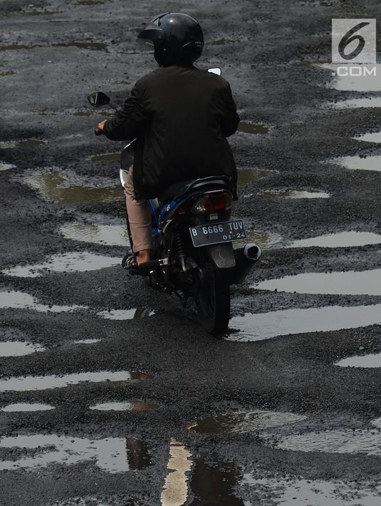 Pengendara sepeda motor menghindari jalan yang ruas saat melintasi ruas Jalan Lapangan Ros, Tebet, Jakarta, Sabtu (11/5/2019). Jalan-jalan berlubang yang terisi air tersebut dapat mengakibatkan kecelakaan bagi pengendara kendaraan bermotor. (merdeka.com/Imam Buhori)
