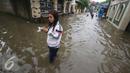 Warga melintasi banjir yang menggenangi Jalan Ketapang di kawasan Pasar Minggu, Jakarta, Selasa (4/10). Banjir yang berasal dari luapan Kali Anur tersebut menyebabkan Jalan Ketapang tidak bisa dilewati kendaraan. (Liputan6.com/Immanuel Antonius)