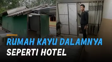 Aksi seorang pria memperlihatkan rumah kayu yang beda dari lainnya.