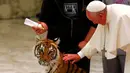  Paus Francis saat ingin membelai seekor harimau di tengah acara sirkus jalanan yang digelar di Aula Paulus VI di Vatikan (16/6).Meskipun sedikit berhati-hati Paus Francis memegang seekor harimau tersebut. (REUTERS/Tony Gentile)