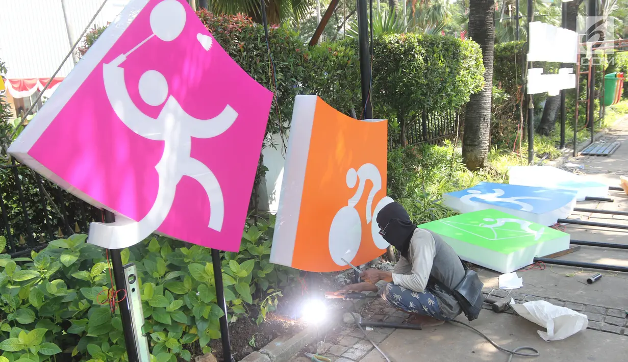 Pekerja memasang neon box Asian Games di depan Balai Kota DKI Jakarta, Jumat (6/7).Lampu neon box berwarna warni yang dipasang menggambarkan berbagai cabang olahraga yang akan dipertandingkan dalam Asian Games 2018. (Liputan6.com/Arya Manggala)