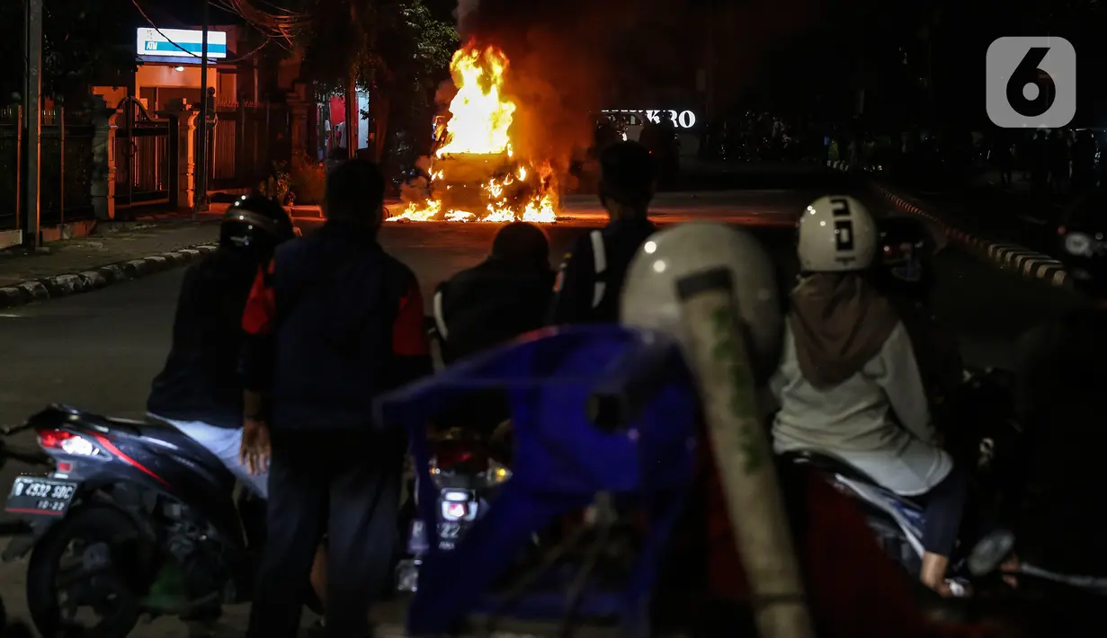 Warga menyaksikan sebuah mobil terbakar di Jalan Asia Afrika, Jakarta, Kamis (18/3/2021) dinihari. Diduga penyebab api adalah akibat dari hubungan pendek arus listrik yang terjadi di bagian mesin. (Liputan6.com/Johan Tallo)