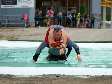 Kontestan pria menggendong pasangannya melewati air saat mengikuti kejuaraan dunia ke-24 lomba lari gendong istri di Sonkajarvi, Finlandia, Sabtu (6/7/2019). Pasangan yang mengikuti lomba ini tidaklah harus benar-benar sudah menikah. (AP Photo/David Keyton)