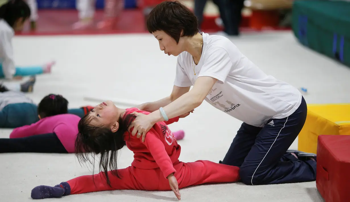 Guru melatih salah seorang murid selama kelas senam di sekolah atletik Shanghai Yangpu Youth Amateur, China (18/5). Latihan keras ini bisa membuat anak-anak menangis dan cedera ini diharapkan mampu menjadikan atlet berkualitas. (REUTERS/Aly Song)