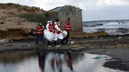 Kelompok Bulan Sabit Merah Libya menggotong kantong mayat berisi jenazah, diduga imigran yang tewas tenggelam di pantai Khoms, sebelah timur Tripoli, Minggu (25/10). Sedikitnya 40 jasad telah ditemukan di pantai Libya. (REUTERS/Ismail Zitouny)