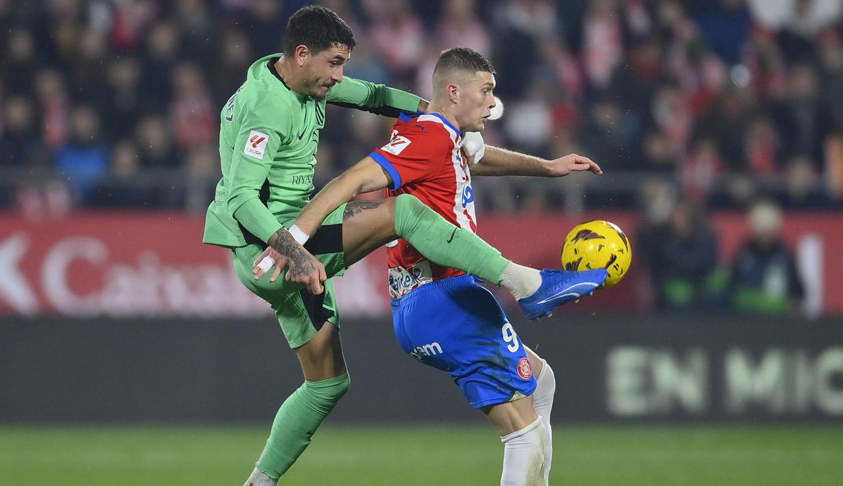 Bek Atletico Madrid, Jose Gimenez (kiri) berebut bola dengan striker Girona, rtem Dovbyk pada laga pekan ke-19 Liga Spanyol 2023/2024 di Montilivi Stadium, Girona, Kamis (4/1/2024) dini hari WIB. (AFP/Pau Barrena)
