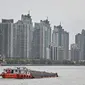 Kapal berlayar di sepanjang Sungai Huangpu di distrik Pudong yang dikunci sebagai tindakan pencegahan Covid-19, di Shanghai (28/3/2022). Jutaan orang di China pusat keuangan dikurung di rumah ketika bagian timur Shanghai dikunci untuk mengekang Covid terbesar di negara itu. (AFP/Hector Retamal)