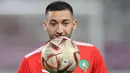 Gelandang Maroko, Hakim Ziyech menatap bola saat ia mengambil bagian dalam sesi latihan di Stadion Al Duhail SC di Doha pada 13 Desember 2022. Maroko akan bertanding melawan Prancis dalam pertandingan semifinal Piala Dunia 2022 di Stadion Al Bayt, Al Khor, Kamis (15/12/2022) pukul 02.00 WIB. (AFP/Karim Jaafar)