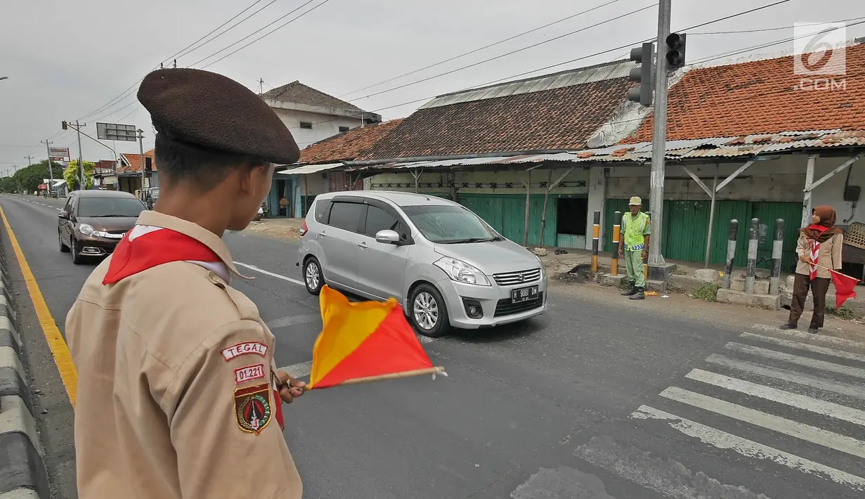 Anggota Pramuka membantu mengatur lalu lintas di jalur mudik kawasan pasar Surodadi, Tegal  Jawa Tengah, Senin (3/6/2019). Puluhan anggota Pramuka  membantu polisi mengatur lalu lintas selama arus mudik maupun arus balik. (Liputan6.com/Herman Zakharia)