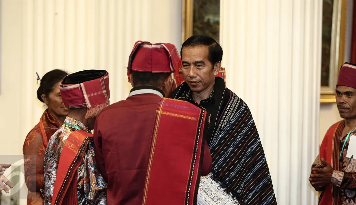 Presiden Joko Widodo (Jokowi) bereaksi setelah diberikan kain ulos oleh Pemangku Hutan Adat dari Tombak Haminjon (Kemenyan) Provinsi Sumatera Utara usai pencanangan pengakuan Hutan Adat di Istana Negara Jakarta, Jumat (30/12). (Liputan6.com/Faizal Fanani)