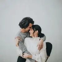 Dengan latar dinding putih polos, Tyas dan Tengku tampak serasi mengenakan sweater. [@@morden.co]