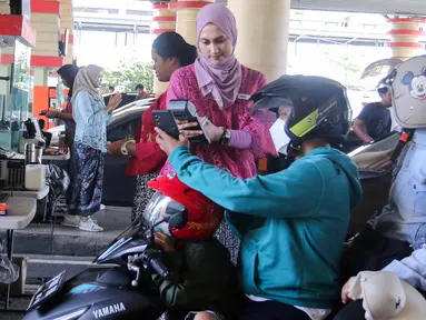Petugas melayani pengunjung saat tiba di gerbang pintu Ancol Jakarta, Minggu (21/4/2024). (Liputan6.com/Herman Zakharia)