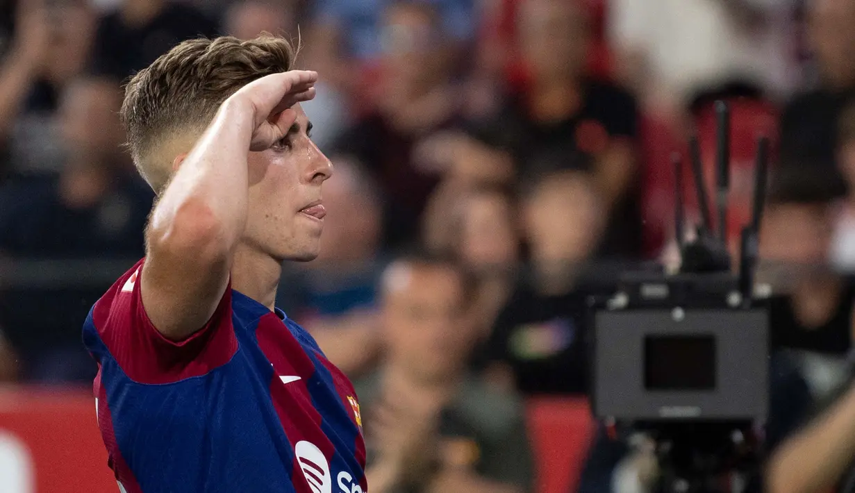 Gelandang Barcelona, Fermin Lopez memberi hormat kepada suporter saat merayakan gol pada pertandingan sepak bola Liga Spanyol melawan Sevilla FC di stadion Ramon Sanchez Pizjuan, Sevilla, 26 Mei 2024. (JORGE GUERRERO/AFP)