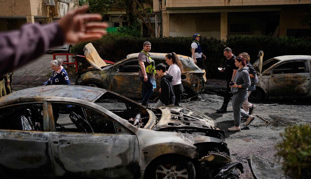Warga dan pasukan keamanan Israel memeriksa lokasi yang terkena serangan rudal Iran di Petah Tikva, Israel, Selasa 31 Maret 2026. Serangan rudal balistik Iran kembali menghantam wilayah Petah Tikva, Israel. (AP Photo/Ohad Zwigenberg)