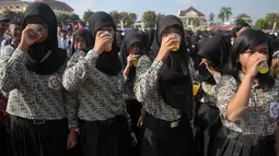 Sejumlah pelajar saat minum jamu bersama di Alun-Alun Satya Negara Sukoharjo, Jawa Tengah, Rabu (1/4/2015). Kegiatan tersebut dalam rangka pelestarian jamu ke masyarakat nasional maupun internasional. (Liputan6.com/Johan Tallo)
