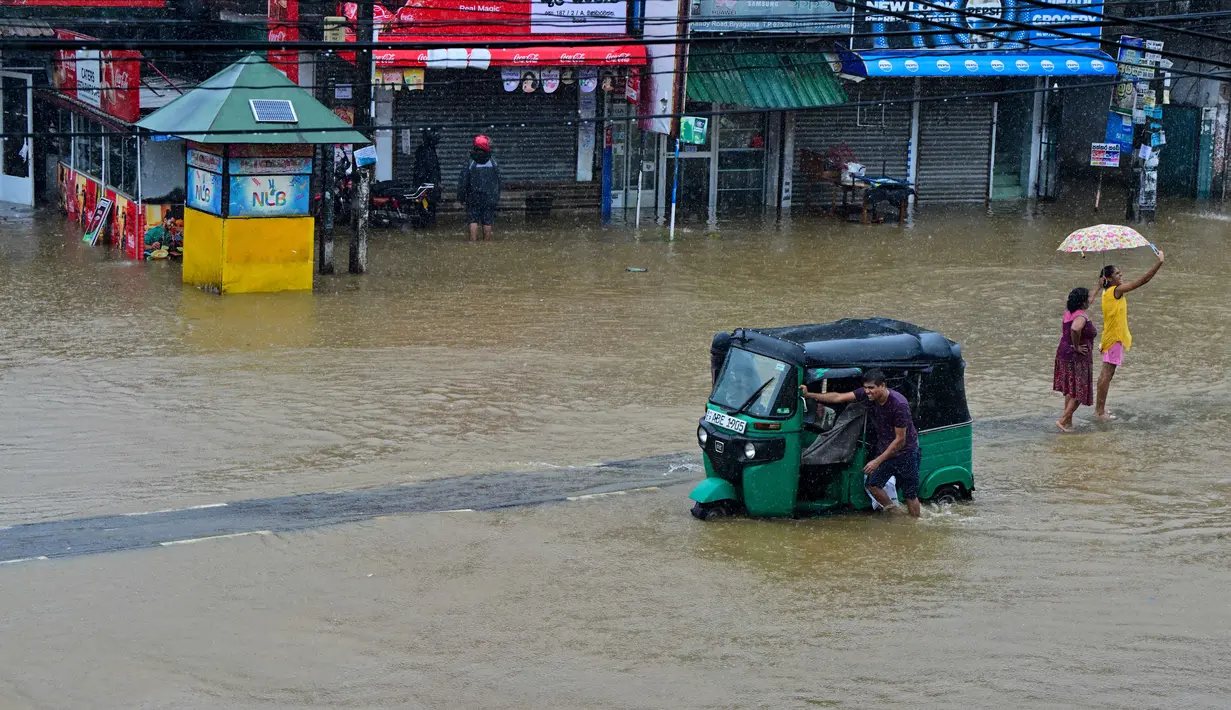 Lebih dari 43.991 orang di 17 distrik dievakuasi ke lokasi yang lebih aman. Tampak dalam foto, seorang pria mendorong becaknya saat mengarungi jalan yang tergenang banjir setelah hujan deras di Kaduwela, pinggiran Kolombo, pada Jumat 28 November 2025. (Ishara S. KODIKARA/AFP)