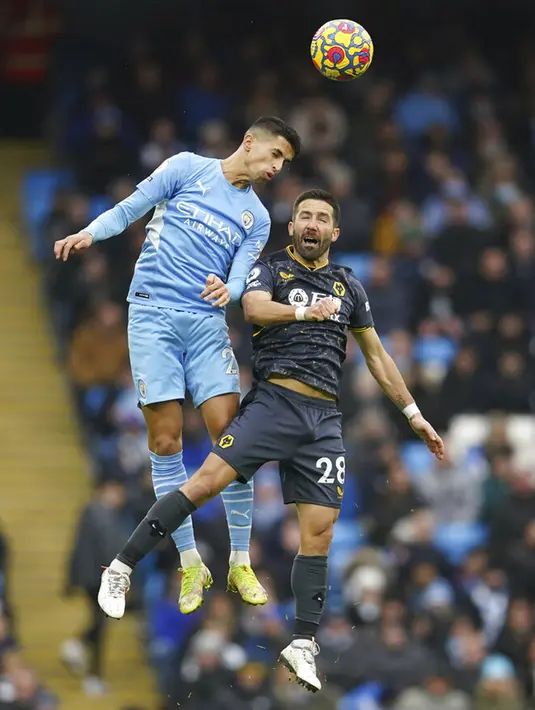 Pemain Manchester City Joao Cancelo (kiri) berebut bola udara dengan pemain Wolverhampton Wanderers Joao Moutinho pada pertandingan sepak bola Liga Inggris di Etihad Stadium, Manchester, Inggris, 11 Desember 2021. Manchester City menang 1-0. (AP Photo/Dave Thompson)