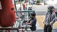 Seorang anak didampingi orangtua mencuci tangan terlebih dahulu sebelum mengikuti program BIAS di Kantor Kelurahan Tamansari, Jakarta, Selasa (24/11/2020). BIAS dipusatkan di kantor kelurahan masing-masing wilayah. (merdeka.com/Iqbal S. Nugroho)