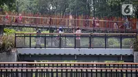 Pengunjung berfoto di jembatan Tebet Eco Park, Jakarta, Selasa (10/5/2022). Warga memanfaatkan libur dengan bermain dan berolahraga di taman terbuka setelah pemerintah memperpanjang masa liburan sekolah hingga tanggal 11 Mei 2022. (Liputan6.com/Faizal Fanani)