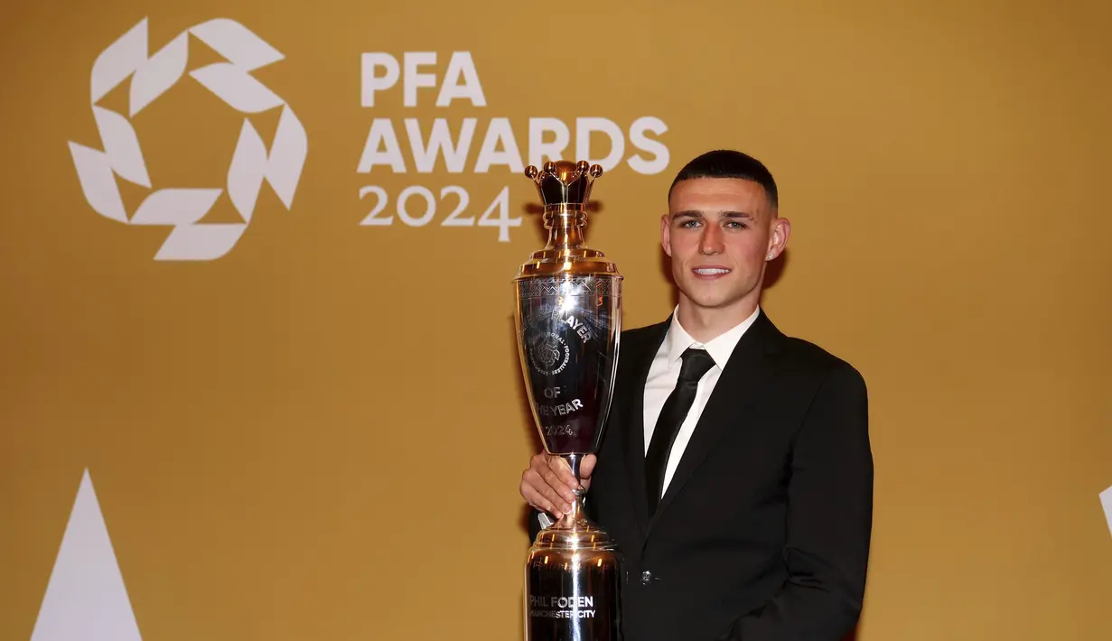 Gelandang Manchester City, Phil Foden berpose dengan trofi penghargaan Pemain Terbaik Pria versi Asosiasi Pemain Sepak Bola Profesional (PFA) di Opera House Manchester, Inggris, Selasa (20/8/2024). (Peter Byrne/PA via AP)