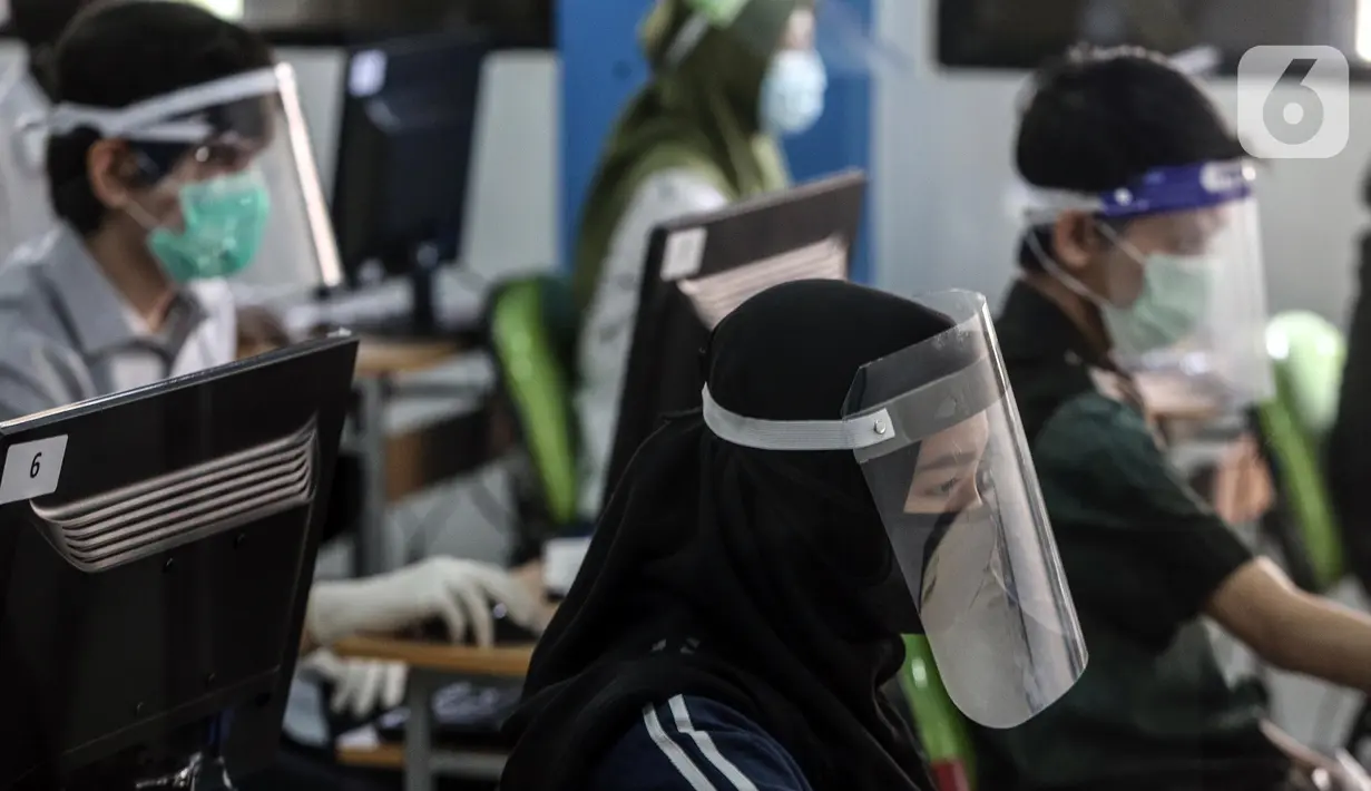 Sejumlah peserta mengenakan masker dan pelindung wajah saat mengikuti Seleksi Bersama Masuk Perguruan Tinggi Negeri (SBMPTN) di Universitan Negeri Jakarta, Minggu (5/7/2020). Sebanyak 42.463 peserta mengikuti SBMPTN dengan prosedur protokol kesehatan. (Liputan6.com/Faizal Fanani)