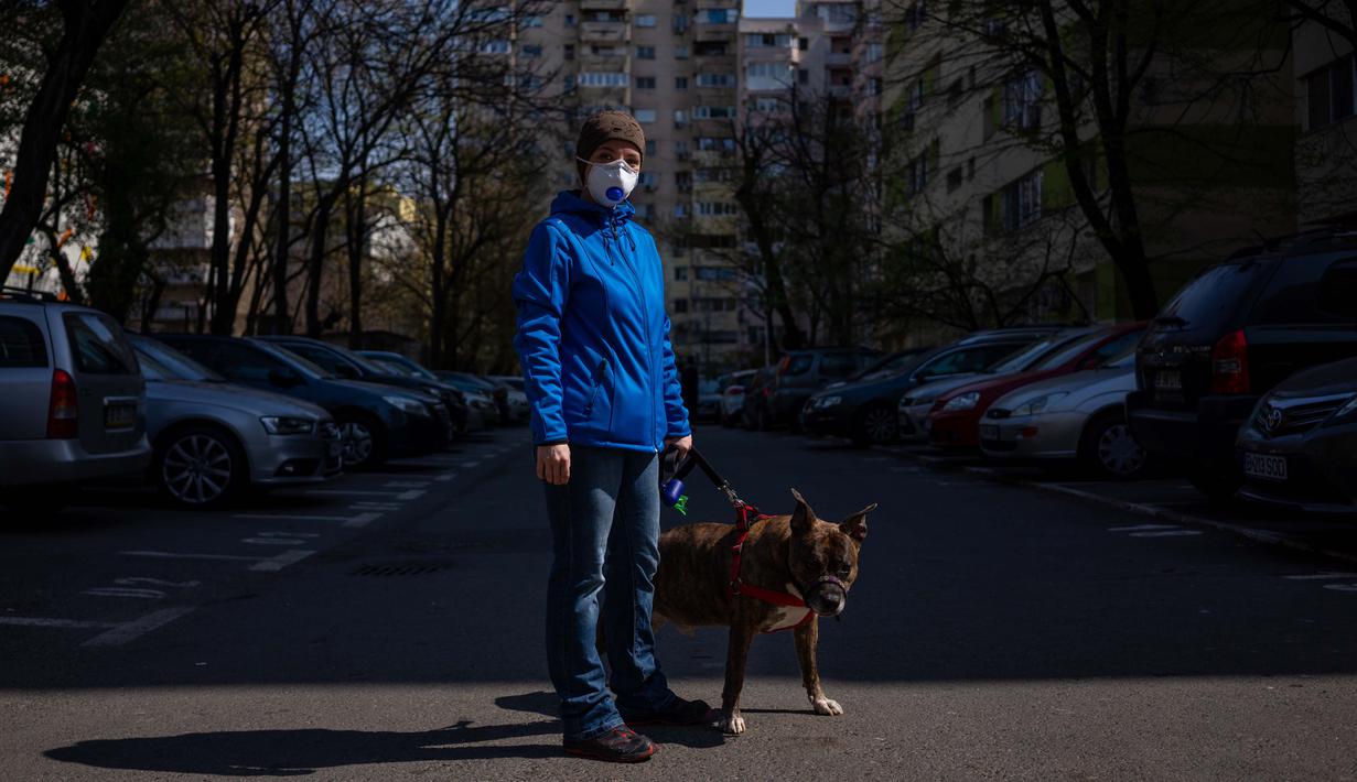 Alexandra Robu (34) berpose dengan anjingnya Dante (12) di Bucharest (29/3/2020). Undang-undang militer, yang disahkan pemerintah Rumania untuk mengurangi penyebaran virus corona, menyatakan berjalan bersama anjing adalah salah satu  kegiatan yang masih diizinkan. (AFP/Andrei Pungovschi)