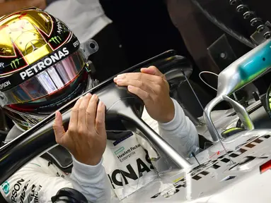 Pembalap Mercedes, Lewis Hamilton memasuki mobilnya saat sesi latihan pertama jelang GP F1 Abu Dhabi di Sirkuit Yas Marina, Jumat (23/11). Hamilton tampil berbeda dengan nomor balap yang melekat pada mobilnya. (GIUSEPPE CACACE/AFP)