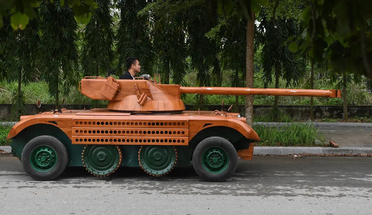 Truong Van Dao duduk tank kayu di daerah perumahan di provinsi Bac Ninh, Vietnam pada 28 Maret 2022. Kendaraan kayu, berdasarkan model EBR105 Prancis dan lengkap dengan meriam replika sepanjang 2,8 meter itu, menghabiskan dana USD11 ribu atau sekitar Rp158 juta. (Nhac NGUYEN /AFP)
