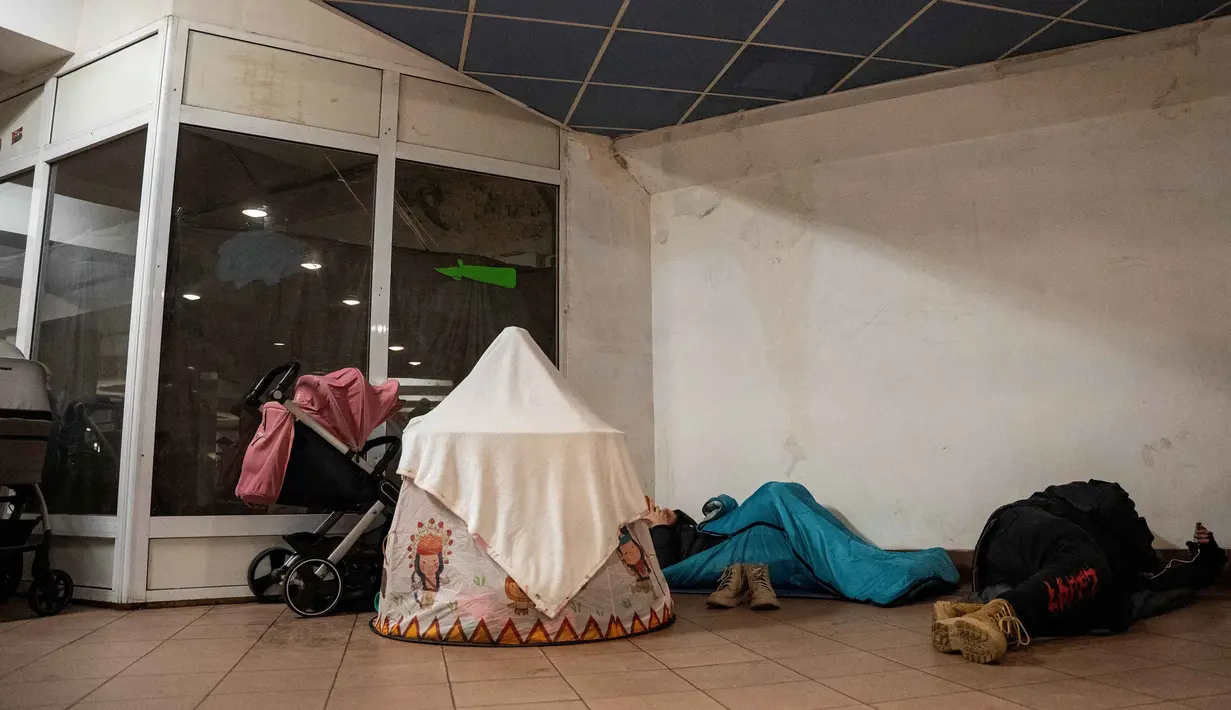 Otoritas setempat mendesak warga untuk tetap berada di dalam tempat perlindungan sampai sirene serangan udara berhenti berbunyi. Tampak dalam foto, warga berlindung di stasiun metro selama serangan pesawat tak berawak dan rudal Rusia di Kyiv, Ukraina, pada 9 Januari 2026 pagi hari waktu setempat, di tengah invasi Rusia ke Ukraina. (Serhii Okunev/AFP)