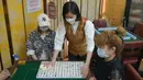 Staf yang mengenakan masker memperagakan langkah-langkah keamanan kepada media di ruang tamu mahjong di Hong Kong, Rabu (28/4/2021). Pelonggaran langkah-langkah terkait COVID-19 berlaku bagi pelanggan dan staf yang telah divaksinasi. (AP Photo/Kin Cheung)