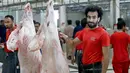 Mohammad Ibraheem saat memotong daging di sebuah rumah jagal hewan di hari ketiga Idul Adha di Kota Kuwait (13/8/2019). Pria 27 tahun ini mendadak terkenal karena kemiripan wajahnya dengan pemain Liverpool asal Mesir, Mohamed Salah. (AFP Photo/Yasser Al-Zayyat)