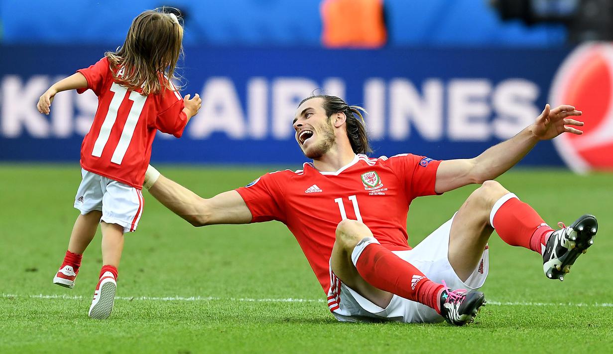 Gareth Bale dan putrinya, Alba Violet bermain ditengah lapangan usai laga melawan Irlandia Utara pada Piala Eropa 2016 di Parc des Princes, Paris, (25/6/2016). Wales Menang 1-0. (EPA/Georgi Licovski)