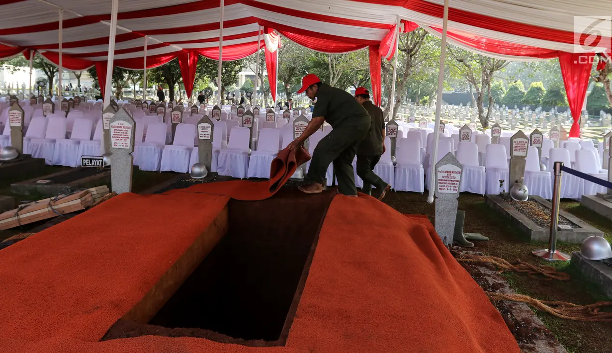 Pekerja menyiapkan karpet merah di makam Presiden ke-3 RI BJ Habibie di TMP Kalibata, Jakarta, Kamis (12/9/2019). Sejumlah petinggi dilaporkan bakal hadir menghadiri pemakaman Habibie. (Liputan6.com/Herman Zakharia)