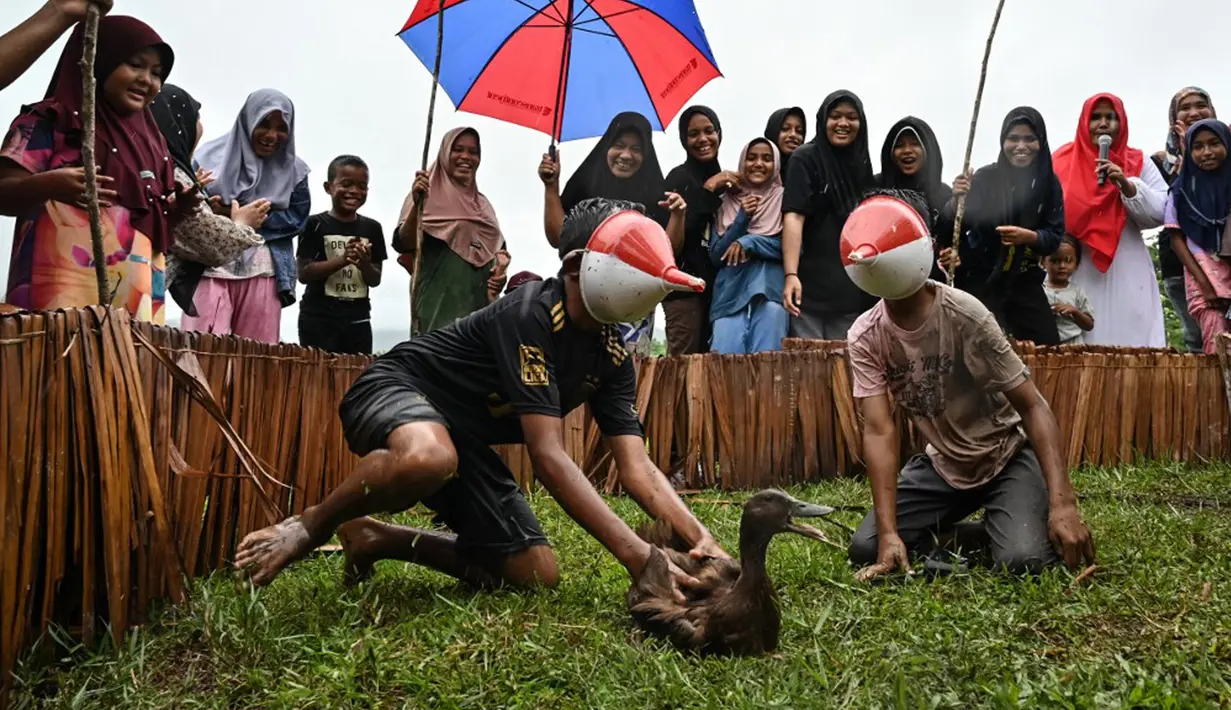 Anak-anak dengan wajah tertutup corong mengikuti lomba berburu bebek saat perayaan menjelang Hari Ulang Tahun (HUT) ke-78 Republik Indonesia (RI) di Desa Wisata Nusa, Banda Aceh, Aceh, Rabu (16/8/2023). (CHAIDEER MAHYUDDIN/AFP)