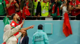 Gelandang Maroko #17 Sofiane Boufal merayakan bersama ibunya setelah lolos ke semifinal dengan mengalahkan Portugal pada babak 8 besar Piala Dunia 2022 di Stadion Al-Thumama di Doha, Sabtu (10/12/2022). Sofiane Boufal menghampiri ibunya yang berada di tepi lapangan. (Photo by Odd ANDERSEN / AFP)