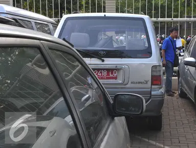 Peserta lelang mengecek mobil dinas KPK yang akan dilelang di halaman KPK, Selasa (1/9/2015). KPK akan melelang 21 mobil dan 8 motor operasional yang sudah tidak digunakan lagi pada Rabu (2/9) melalui KPKNL Jakarta III. (Liputan6.com/Herman Zakharia)