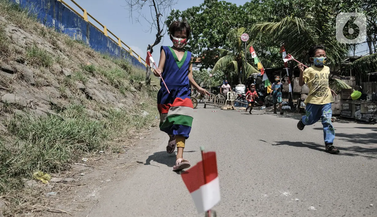 Anak-anak dengan masker mengikuti perlombaan memasukkan bendera ke dalam botol memperingati HUT ke-75 RI di Kampung Nelayan, Cilincing, Jakarta, Senin (17/8/2020). Meski dilarang menggelar perlombaan akibat Covid-19, warga di Kampung Nelayan tetap mengadakan lomba 17-an. (merdeka.com/Iqbal Nugroho)