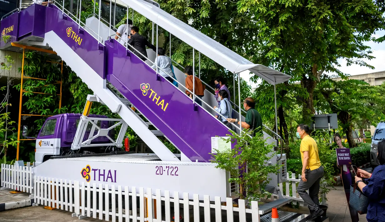 Orang-orang menaiki garbarata, yang biasanya digunakan Ppenumpang untuk naik pesawat, di restoran pop-up bertema kabin pesawat di kantor pusat Thai Airways di Bangkok, 10 September 2020. Restoran ini akan terus buka di Kantor Pusat Thai Airways setiap Rabu hingga Jumat. (Mladen ANTONOV/AFP)
