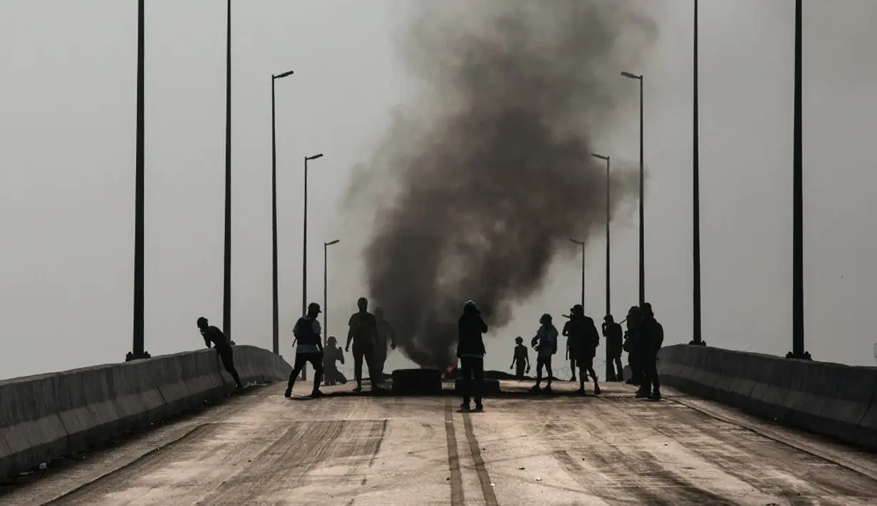Para pengunjuk rasa berdiri dekat ban yang terbakar selama tindakan keras oleh pasukan keamanan terhadap demonstrasi menentang kudeta militer di Yangon, Myanmar, 16 Maret 2021. (STR/AFP)