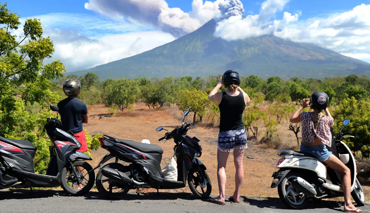Sejumlah turis mengabadikan pemandangan erupsi Gunung Agung di Kabupaten Karangasem, Bali, Jumat (6/7). Mereka sibuk mengabadikan semburan abu vulkanik Gunung Agung.  (AFP FOTO / Sonny Tumbelaka)