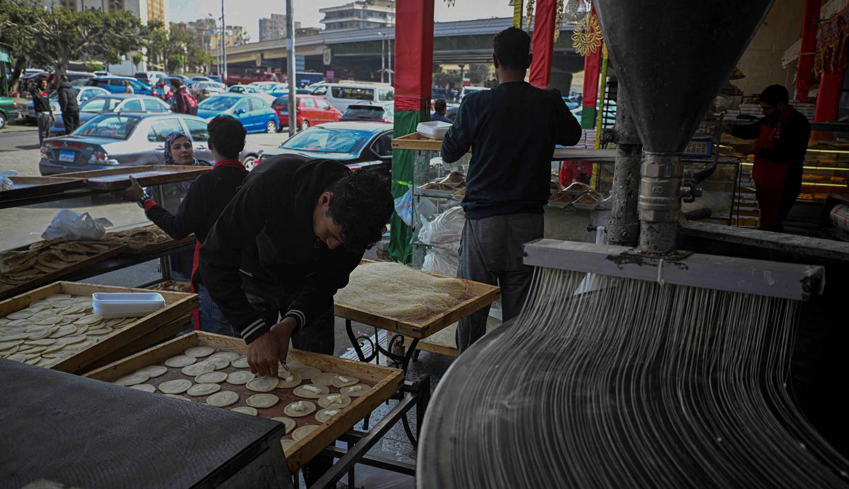 Qatayef, yang sangat populer saat Ramadan, merupakan kue atau kudapan khas tradisional Timur Tengah berbentuk pancake tipis berpori. Tampak dalam foto, para pembuat roti Mesir menyiapkan kue tradisional Qatayef (kiri) dan Kunafa (kanan), yang dibuat selama bulan suci Ramadan, di tokonya, Kairo, Mesir, pada Kamis 12 Maret 2026. (Khaled DESOUKI/AFP)
