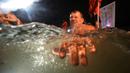 Seorang penganut Kristen Ortodoks Rusia berendam dalam air es saat perayaan Epiphany tradisional di St. Petersburg, Rusia, 19 Januari 2022. Ribuan penganut Kristen Ortodoks Rusia merayakan Epiphany dengan membenamkan diri dalam air dingin. (AP Photo/Dmitri Lovetsky)