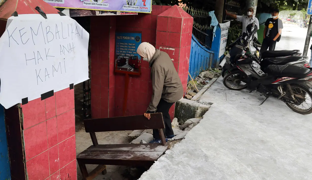 Seseorang berjalan masuk melintasi jalan darurat yang dibuat pihak sekolah di SDN Pondok Cina 1, Depok, Jawa Barat, Rabu (9/11/2022). Pembangunan trotoar Jalan Margonda Raya yang tidak membuat jalan darurat untuk siswa tersebut menghalangi pintu masuk SDN Pondok Cina 1 serta membahayakan siswa. (Liputan6.com/Herman Zakharia)