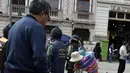 Tukang semir sepatu bertopeng melayani pelanggannya di kawasan La Paz, Bolivia (29/11). Dengan menutup wajahnya para tukang semir ini menyembunyikan identitas karena pekerjaan tersebut dipandang rendah oleh masyarakat lokal. (AFP PHOTO/Aizar Raldes)