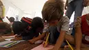 Sejumlah anak pengungsi saat mengikuti kegiatan belajar di sebuah kamp di Ain Issa, Suriah (22/8). Meski belajar di dalam tenda pengungsian, anak-anak tetap antusias mengikuti hari pertama tahun ajaran baru sekolah. (AFP Photo/Delil souleiman)