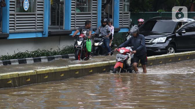 Warga mendorong motornya yang mogok saat menerobos genangan banjir di Jalan Gunung Sahari Jakarta, Selasa (25/2/2020). Hujan yang mengguyur Jakarta sejak Senin (24/2) malam membuat sejumlah kali meluap dan menyebabkan banjir. (Liputan6.com/Helmi Fithriansyah)